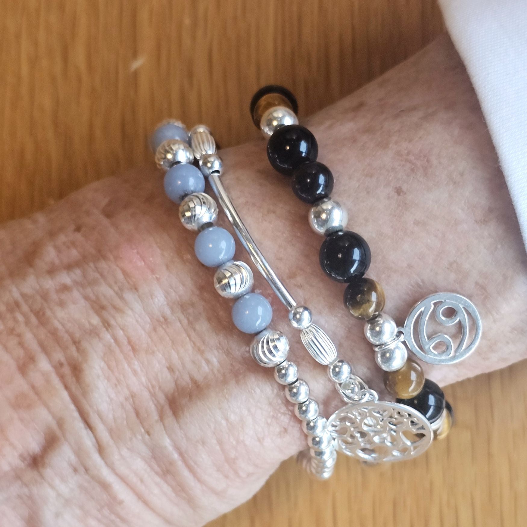 Wrist wearing a stack of Bessie Bae silver beaded bracelets with gemstone charms, perfect for birthday jewellery gifts.