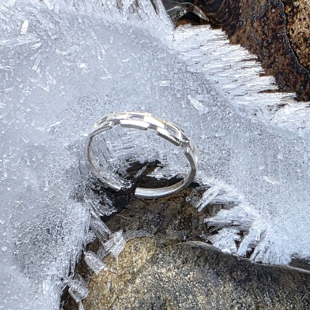 Sterling silver ring resting on icy rocks outdoors, styled in a winter landscape by Bessie Bae.