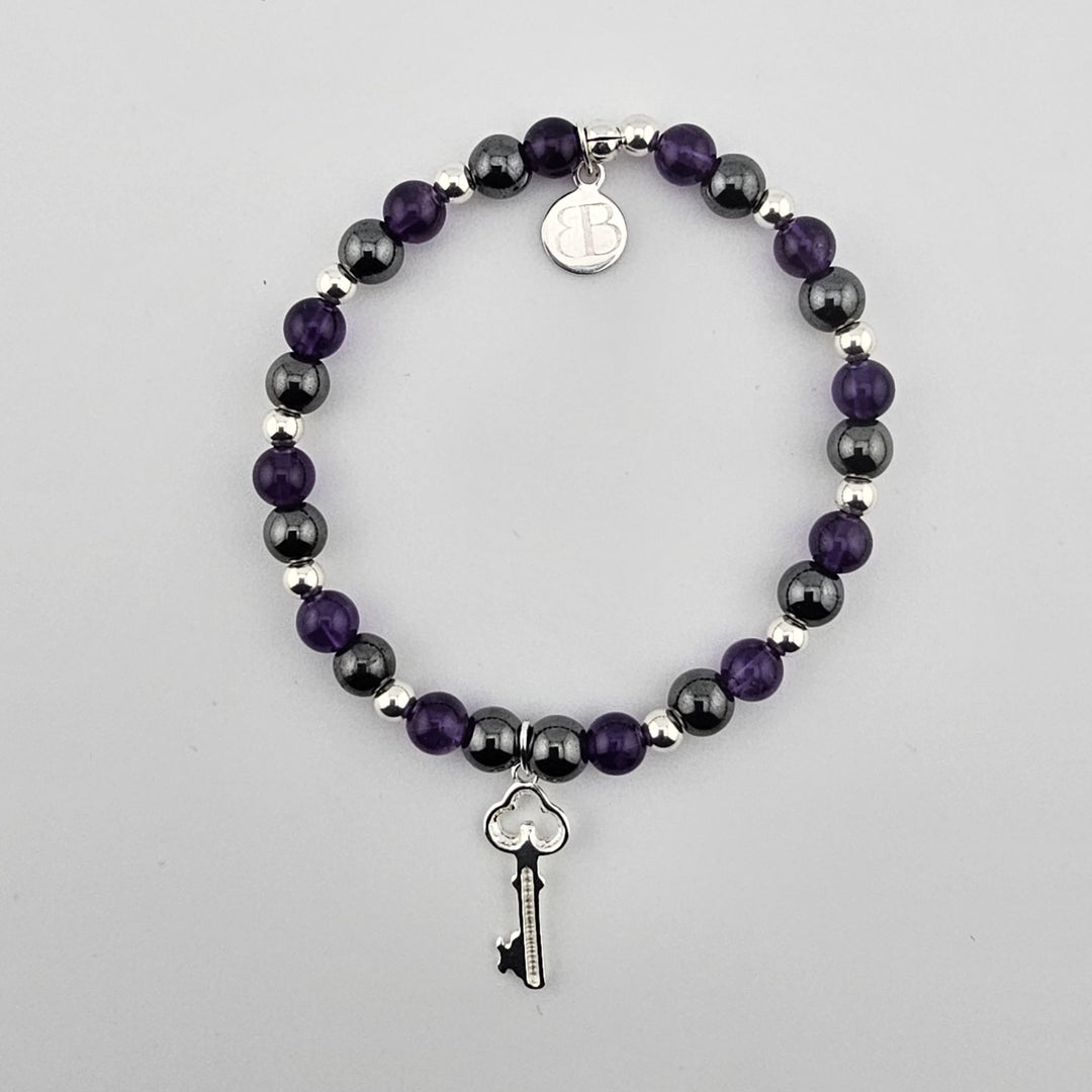 Amethyst an.d hematite gemstone bracelet with sterling silver key charm on white background