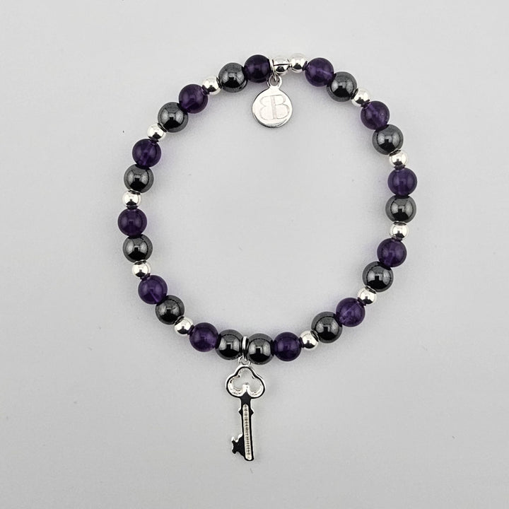 Amethyst an.d hematite gemstone bracelet with sterling silver key charm on white background