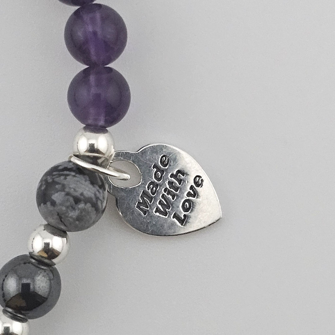 Macro detail of Amethyst and Snowflake Obsidian gemstones with polished Sterling Silver beads.