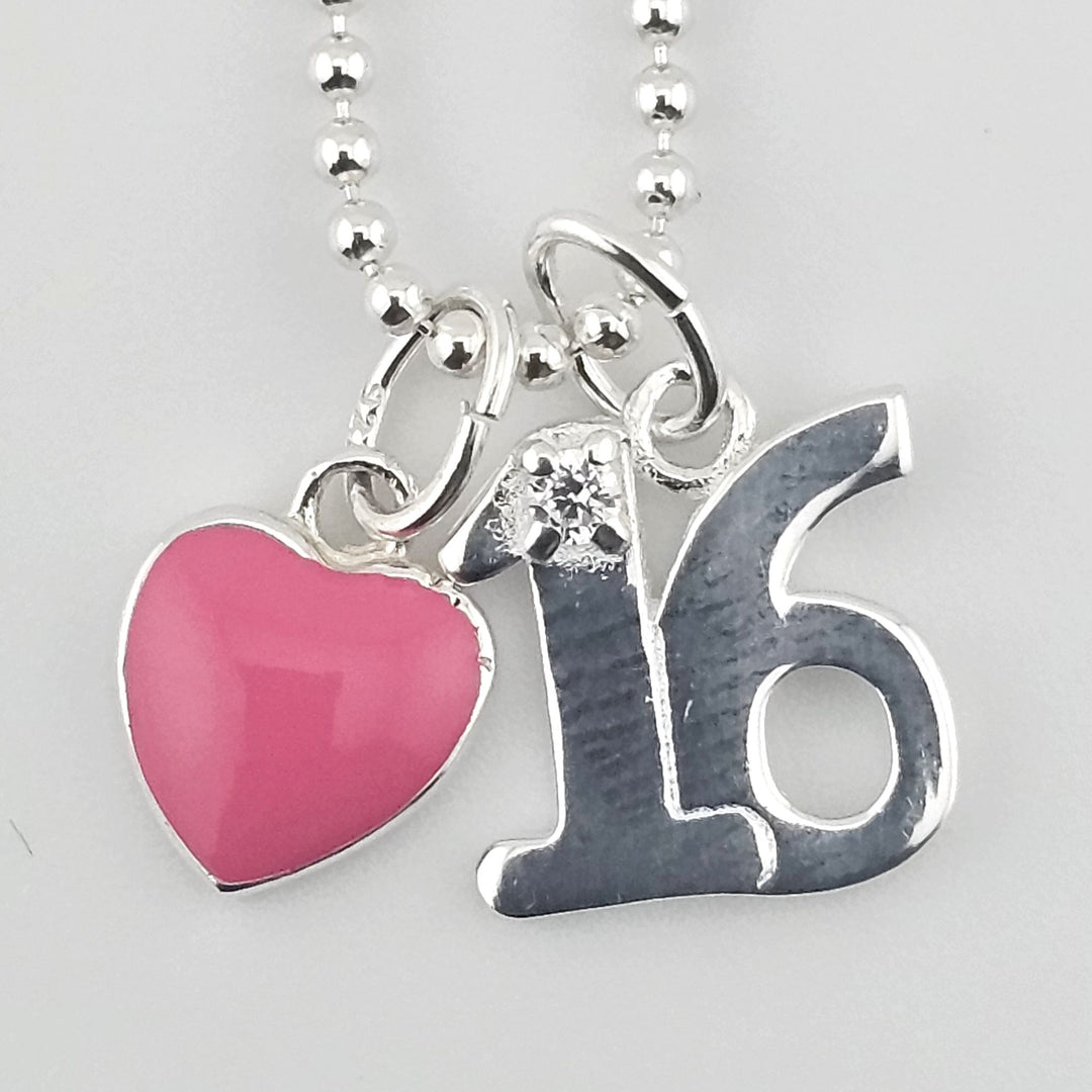 Close-up of sterling silver ‘16’ pendant with pink enamel heart charm.