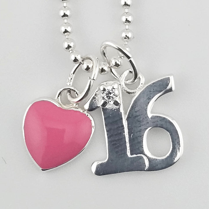 Close-up of sterling silver ‘16’ pendant with pink enamel heart charm.