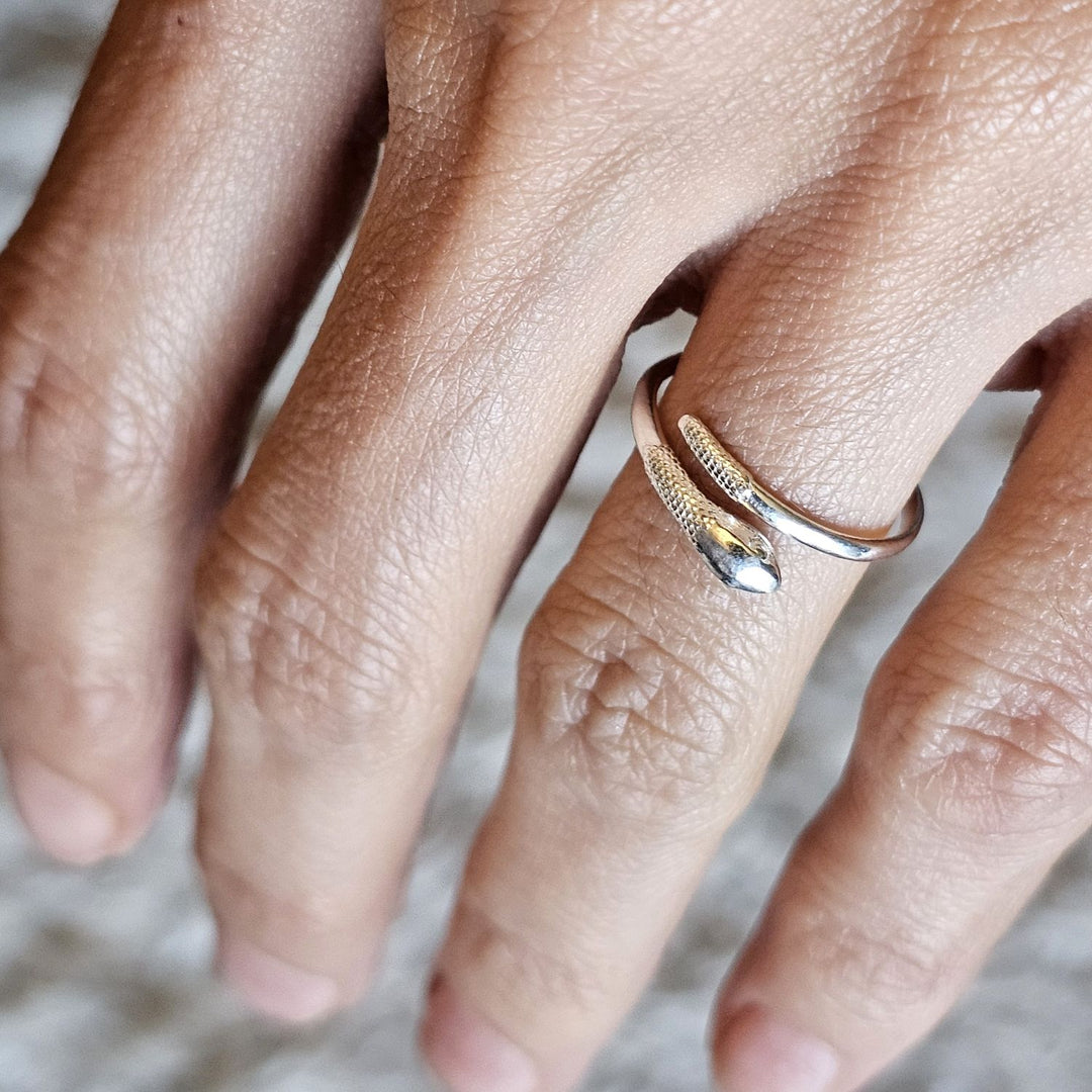 Adjustable sterling silver snake ring worn on a hand.