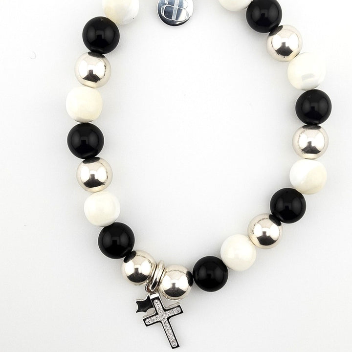 Black onyx and mother of pearl beaded bracelet with sterling silver cross and star charms on white background.