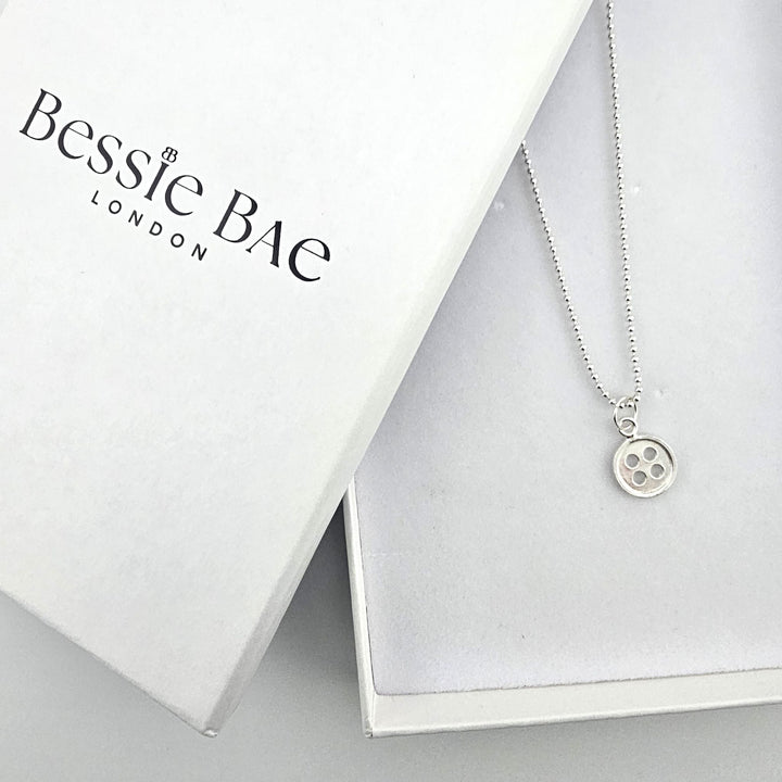 Minimal sterling silver button charm necklace with Bessie Bae packaging.
