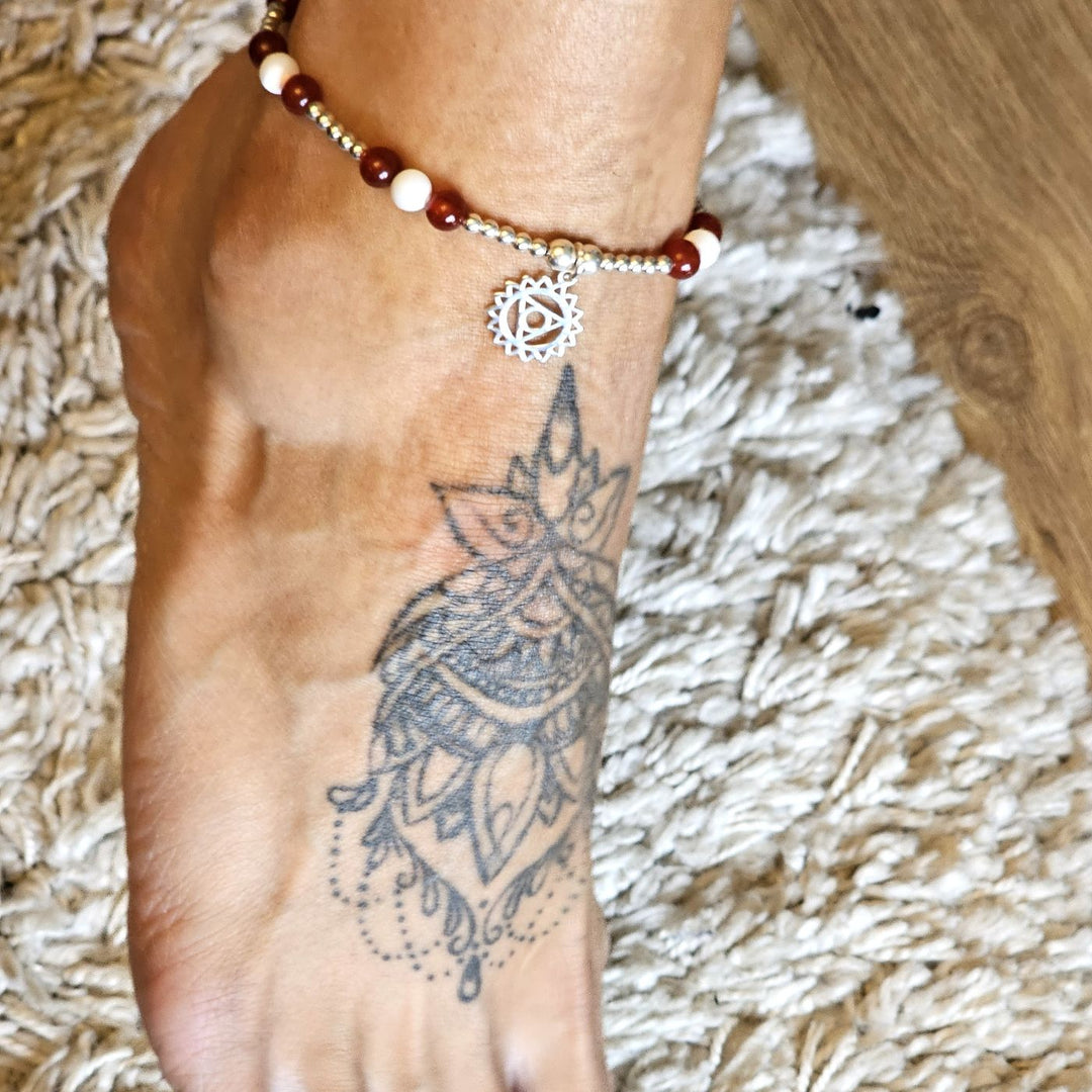 Garnet and mother of pearl throat chakra anklet worn on an ankle with a mandala tattoo.