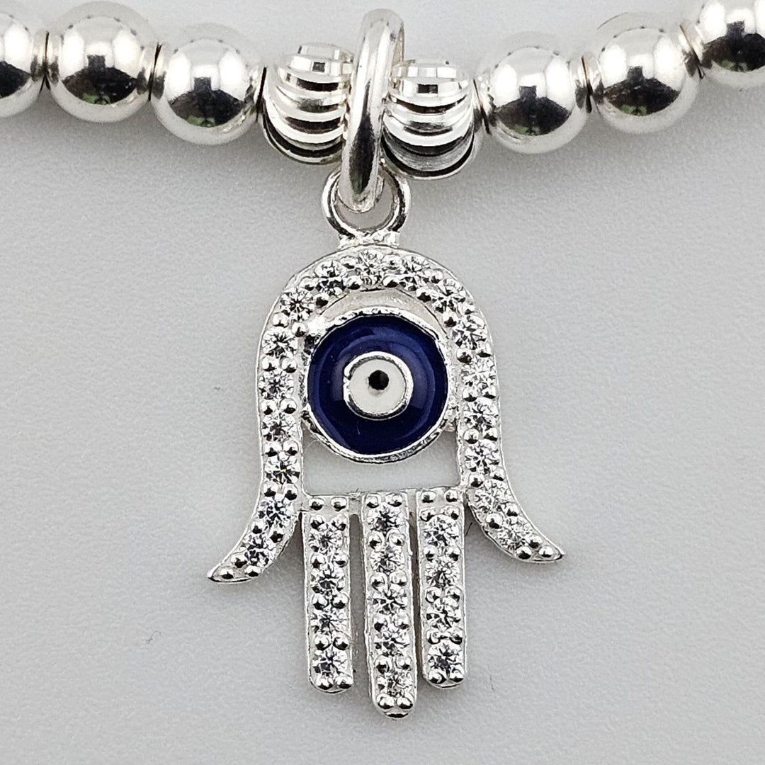Close-up of sterling silver Hamsa hand evil eye charm with sparkling detail.