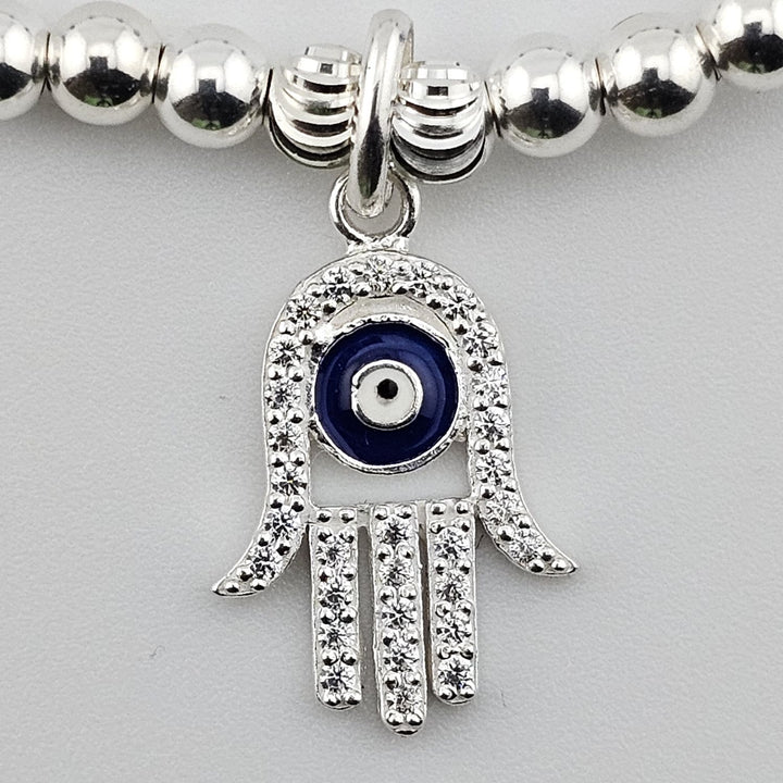 Close-up of sterling silver Hamsa hand evil eye charm with sparkling detail.