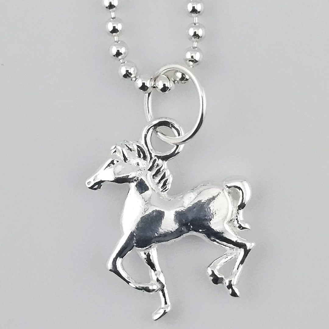 Close-up of sterling silver horse charm on a silver beaded chain.