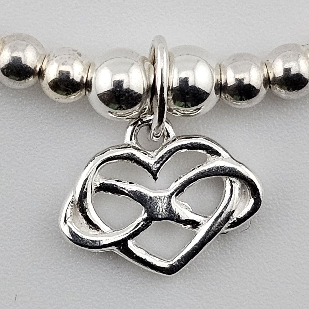 Close-up of interlocking heart charm in sterling silver.