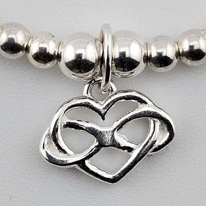 Close-up of interlocking heart charm in sterling silver.
