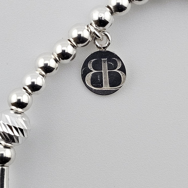 Bessie Bae logo tag attached to sterling silver angel wing bracelet.