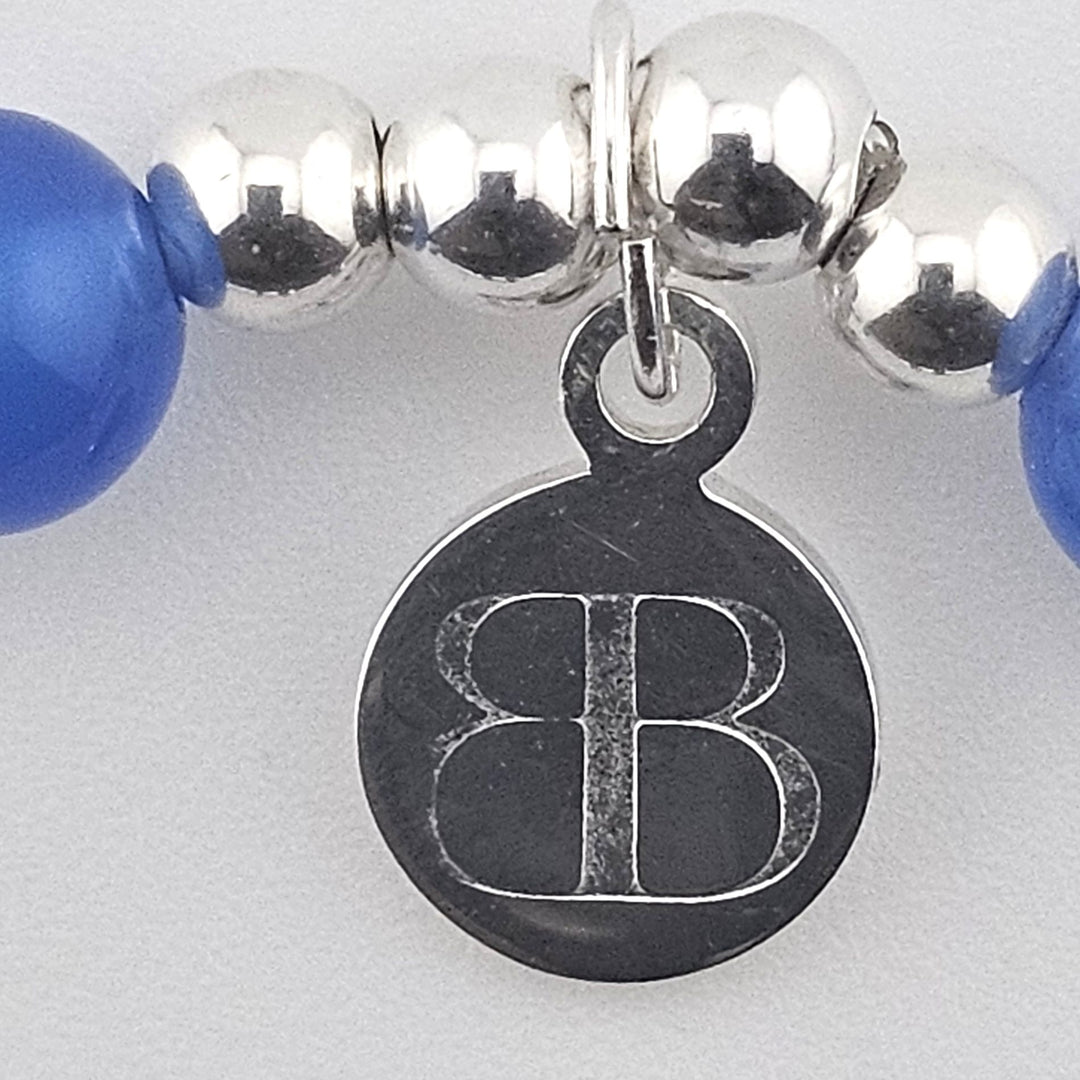 Close-up of Bessie Bae logo charm on bracelet.