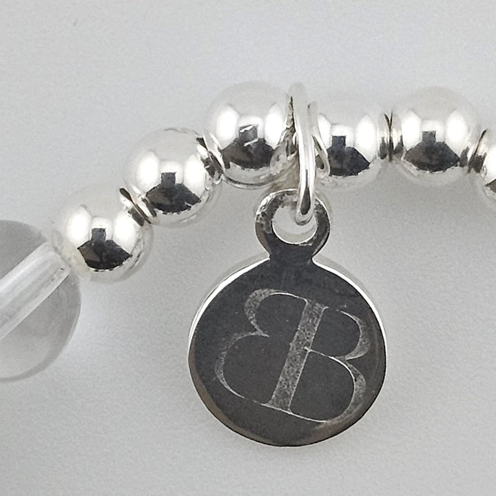 Close-up of Bessie Bae logo charm on bracelet.
