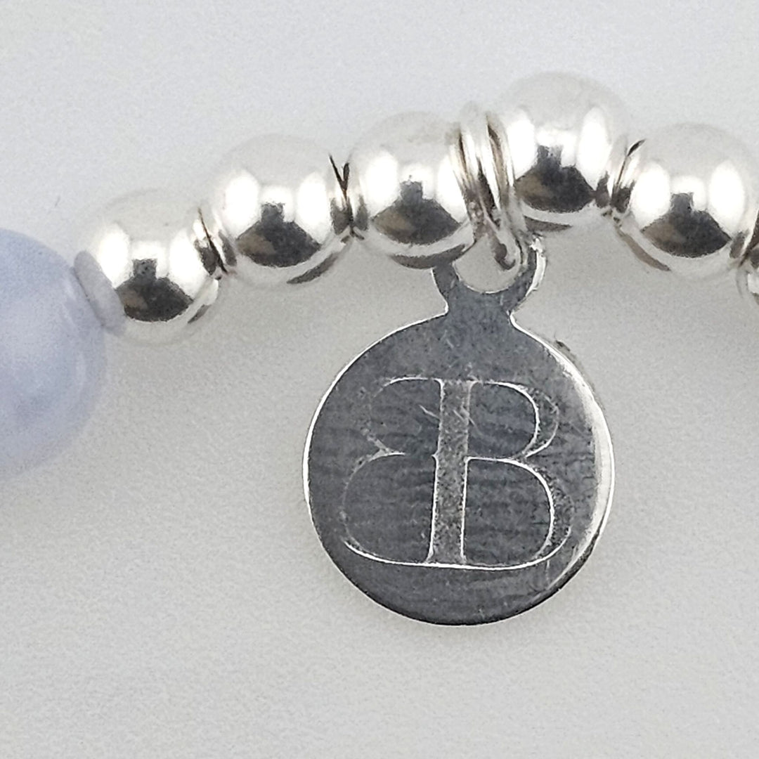 Close-up of Bessie Bae logo charm on bracelet.
