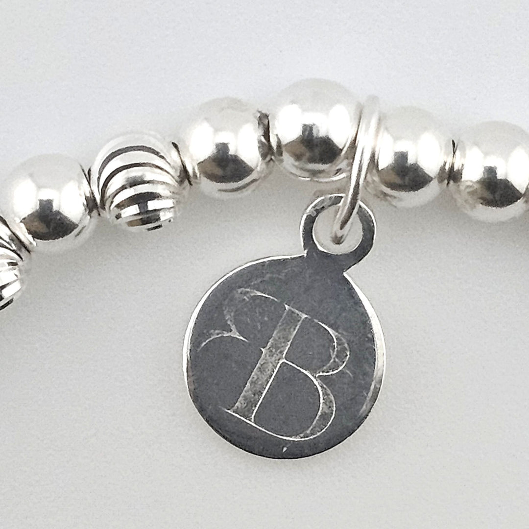 Close-up of Bessie Bae logo charm on bracelet.