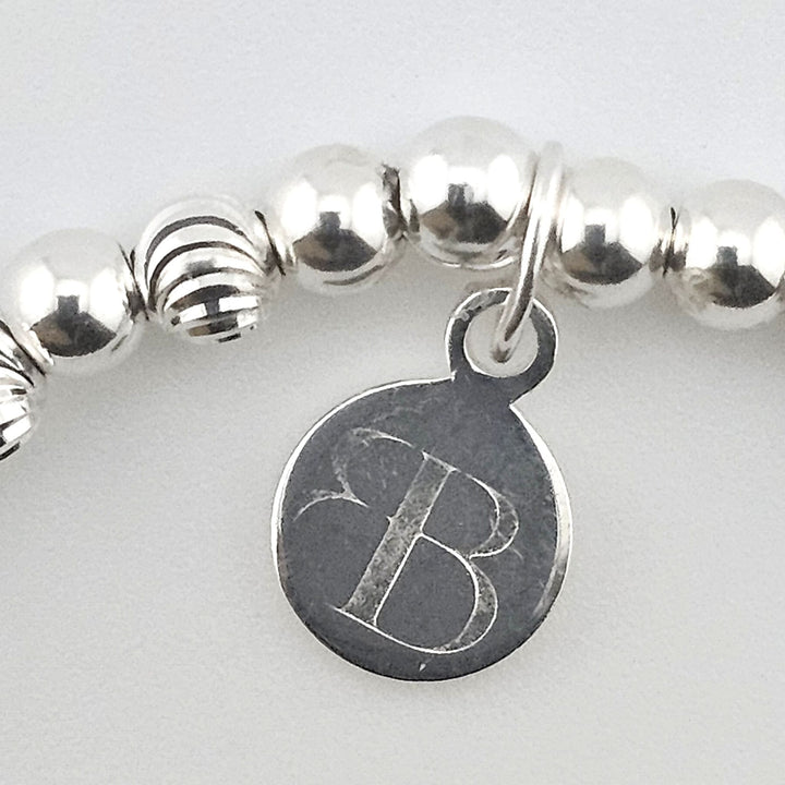 Close-up of Bessie Bae logo charm on bracelet.