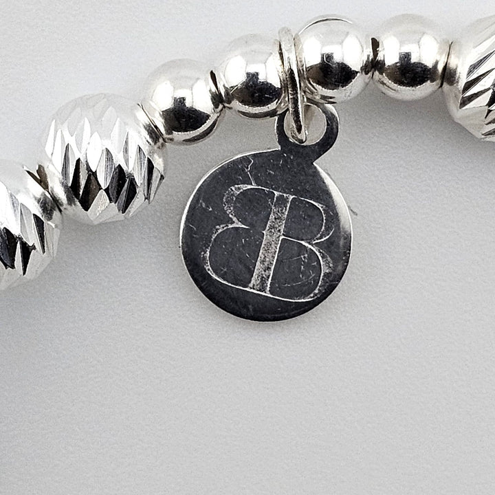 Bessie Bae logo tag attached to sterling silver snowflake bracelet.