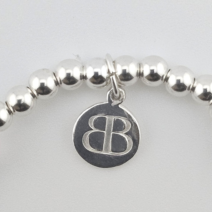 Bessie Bae logo tag on Sterling Silver and Rose Quartz Sweet 16 bracelet.
