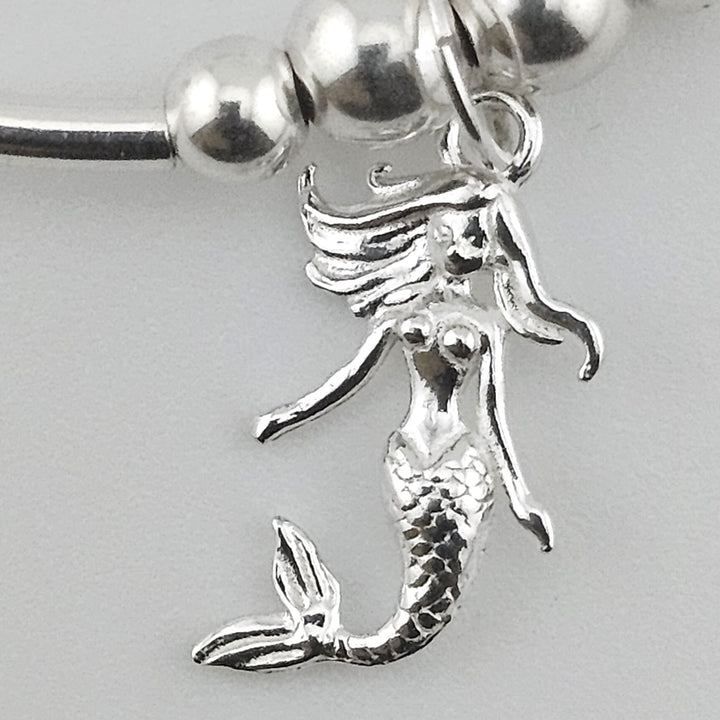 Close-up of mermaid charm in sterling silver.