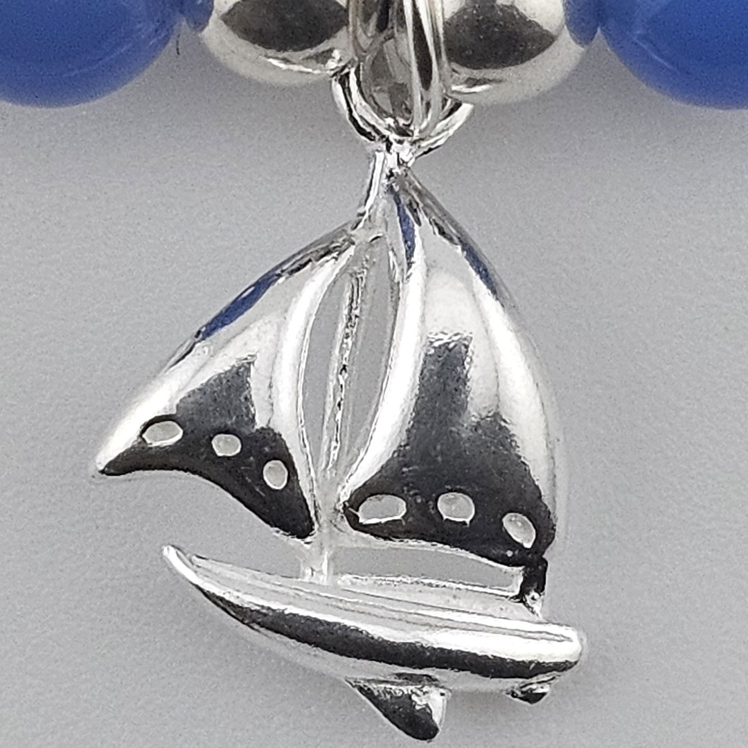Close-up of sterling silver sailboat charm on bracelet.