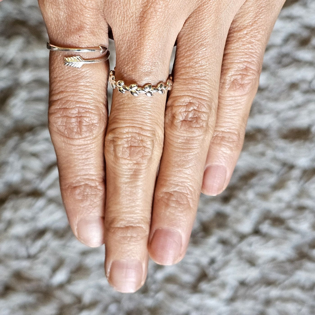 Sterling silver arrow ring and sterling silver crimson leaves ring worn together on a hand.