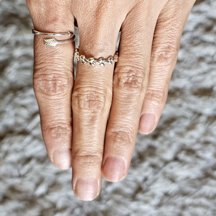 Sterling silver arrow ring and sterling silver crimson leaves ring worn together on a hand.