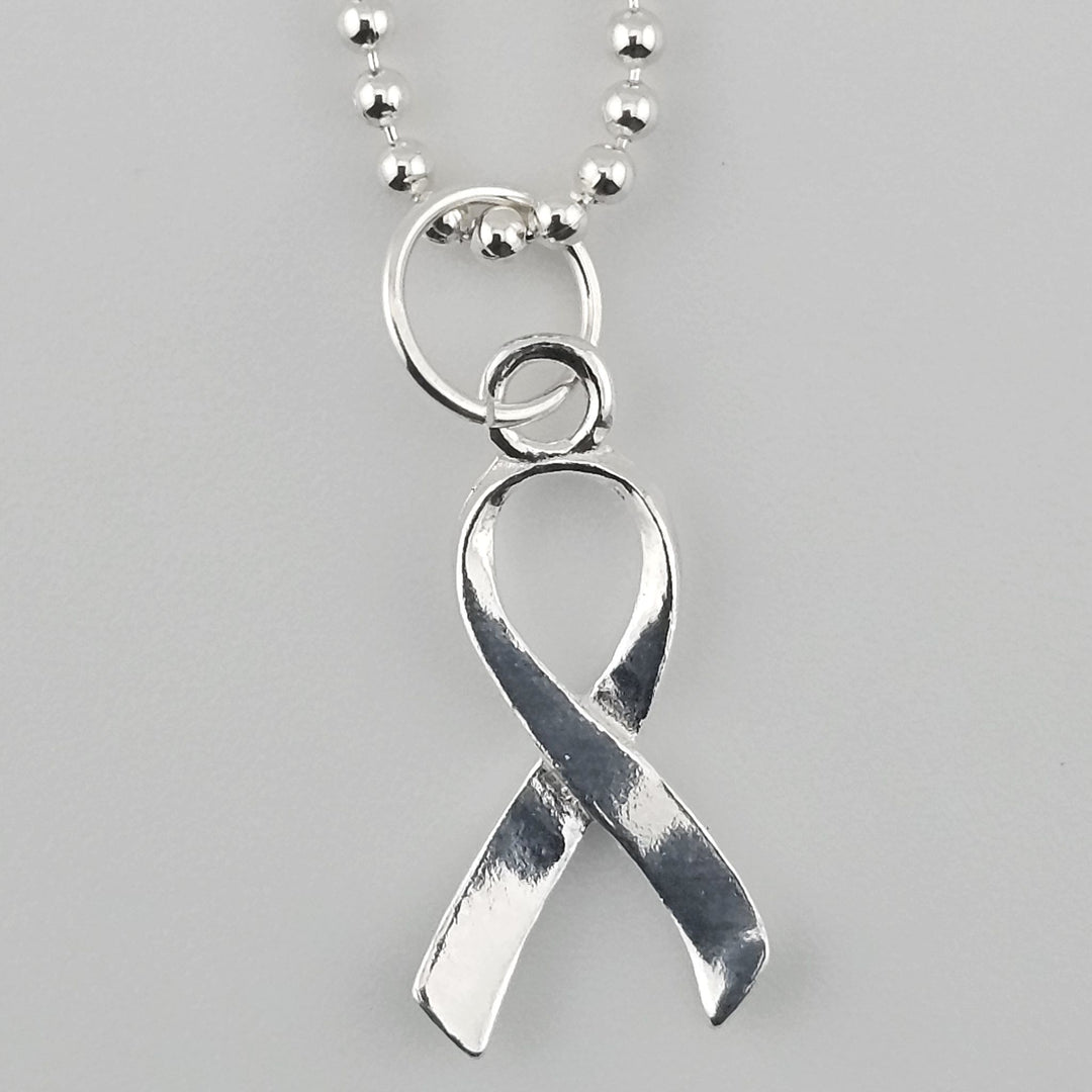 Close-up of sterling silver awareness ribbon pendant with polished finish.