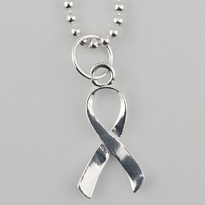 Close-up of sterling silver awareness ribbon pendant with polished finish.