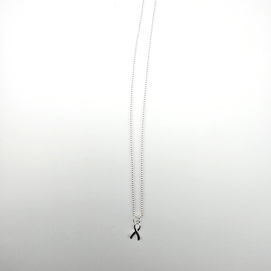 Sterling silver awareness ribbon necklace on a light background.