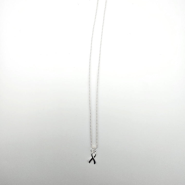 Sterling silver awareness ribbon necklace on a light background.
