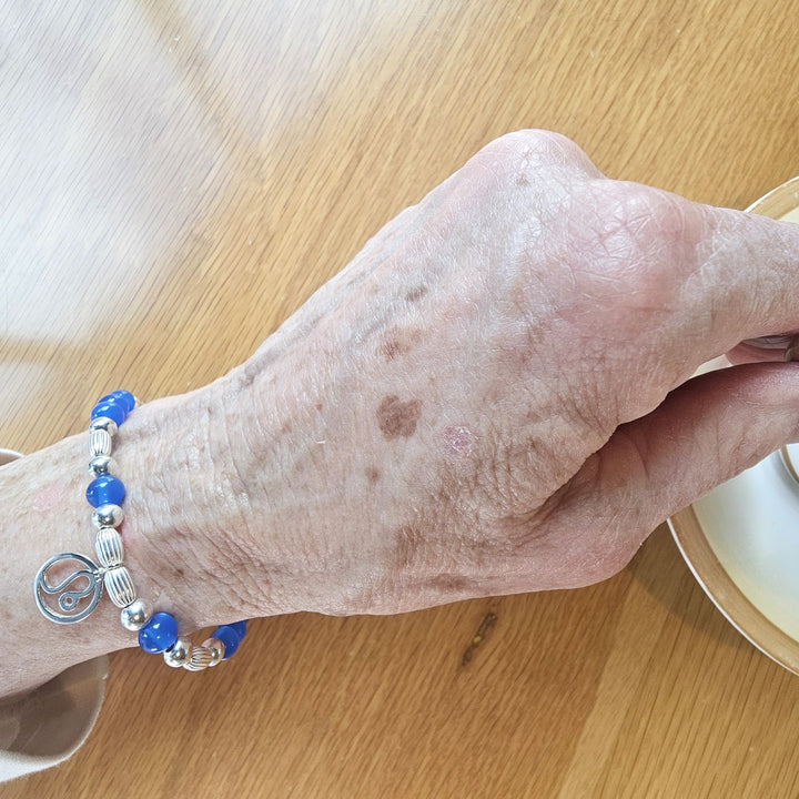 Sterling Silver & Blue Agate Leo Zodiac Bracelet by Bessie Bae on wrist while holding a cup.