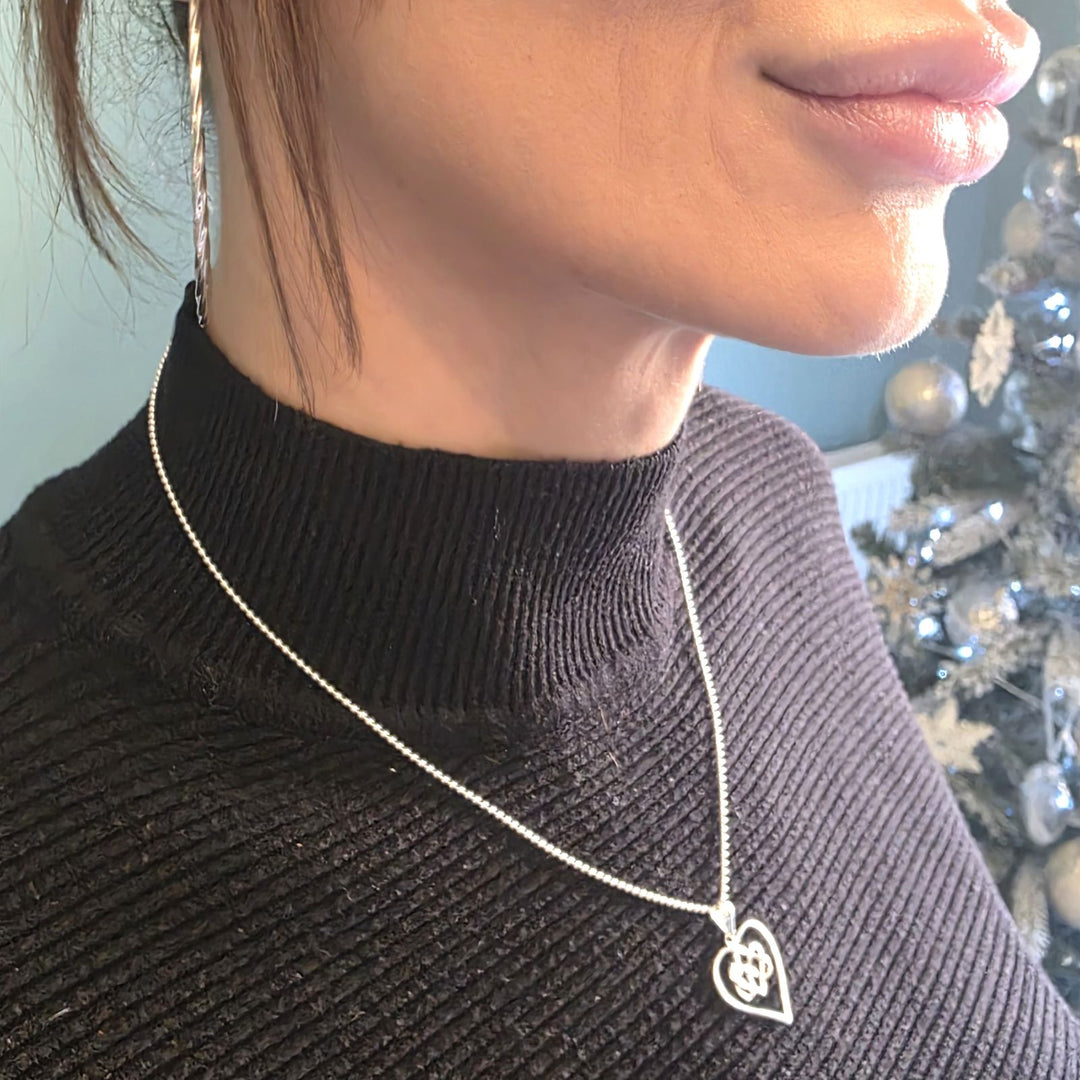 Sterling Silver Celtic Heart necklace with Eternal Love pendant worn on a woman’s neck over a black top.