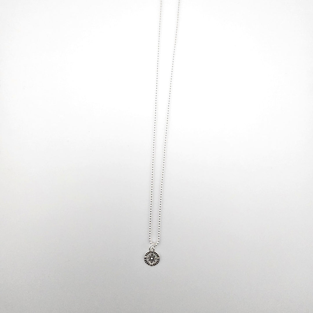 Sterling silver compass star necklace on a fine ball chain, photographed on a white background.