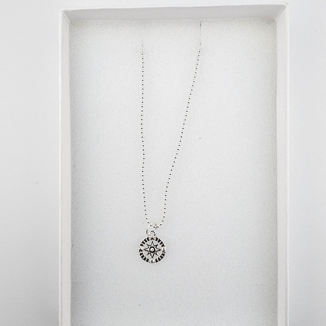 Sterling silver compass star necklace displayed inside a white Bessie Bae gift box.