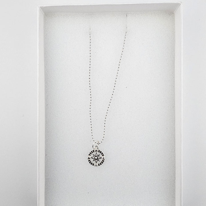 Sterling silver compass star necklace displayed inside a white Bessie Bae gift box.