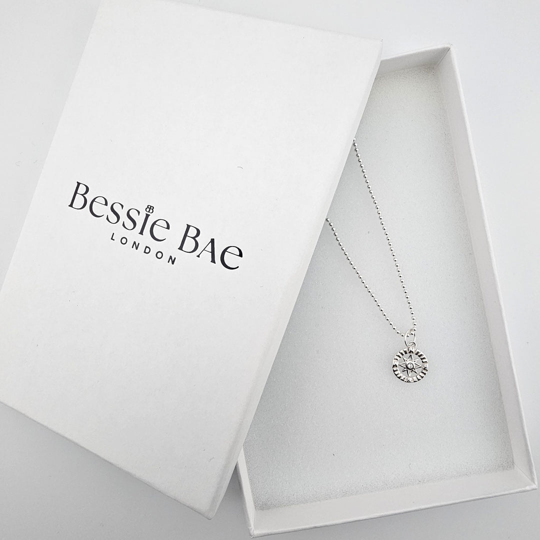 Bessie Bae sterling silver compass star necklace presented in branded gift packaging.