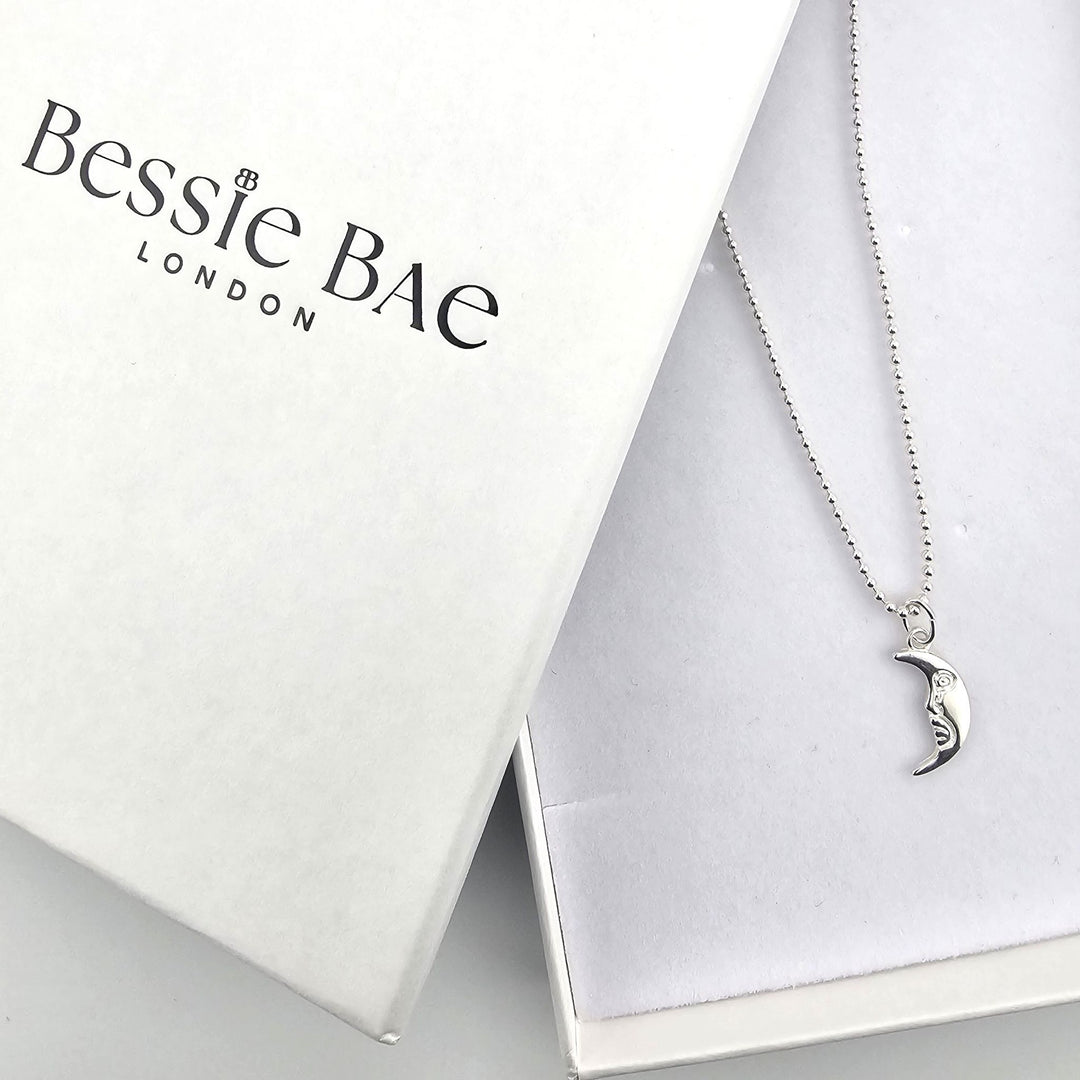 Sterling silver crescent moon necklace shown beside Bessie Bae branded packaging.
