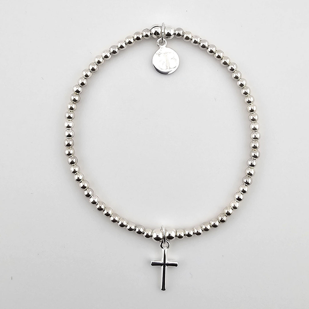 Minimalist sterling silver beaded bracelet with small cross charm.