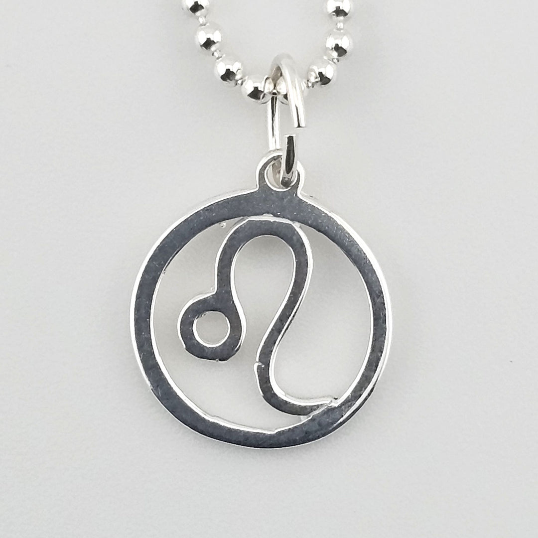 Close-up of sterling silver Leo zodiac pendant inside circular frame.
