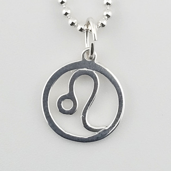 Close-up of sterling silver Leo zodiac pendant inside circular frame.