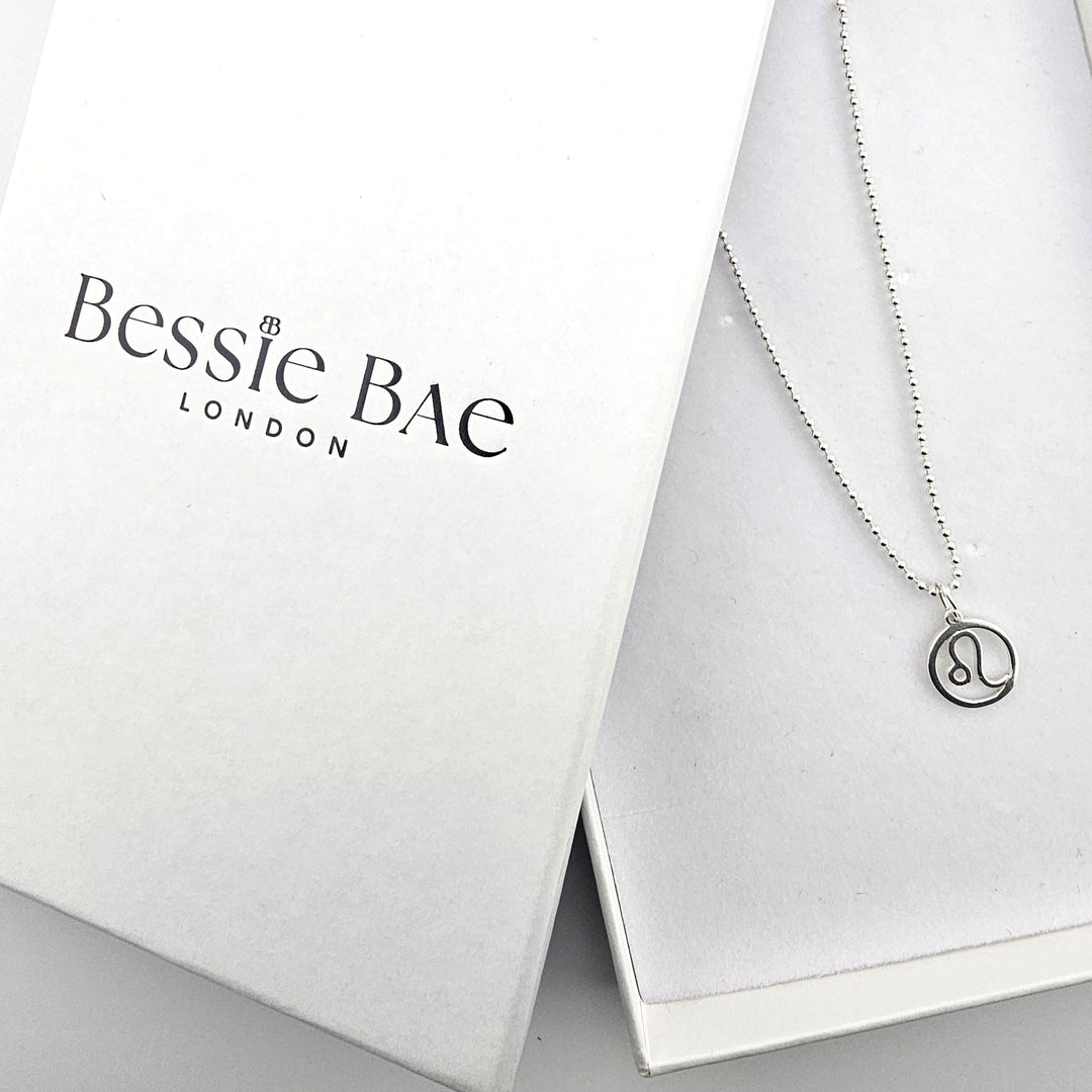 Sterling silver Leo zodiac necklace shown beside Bessie Bae branded packaging.