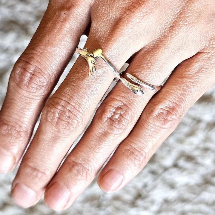 Sterling silver snake ring and sterling silver heart and arrow ring worn together on a hand.