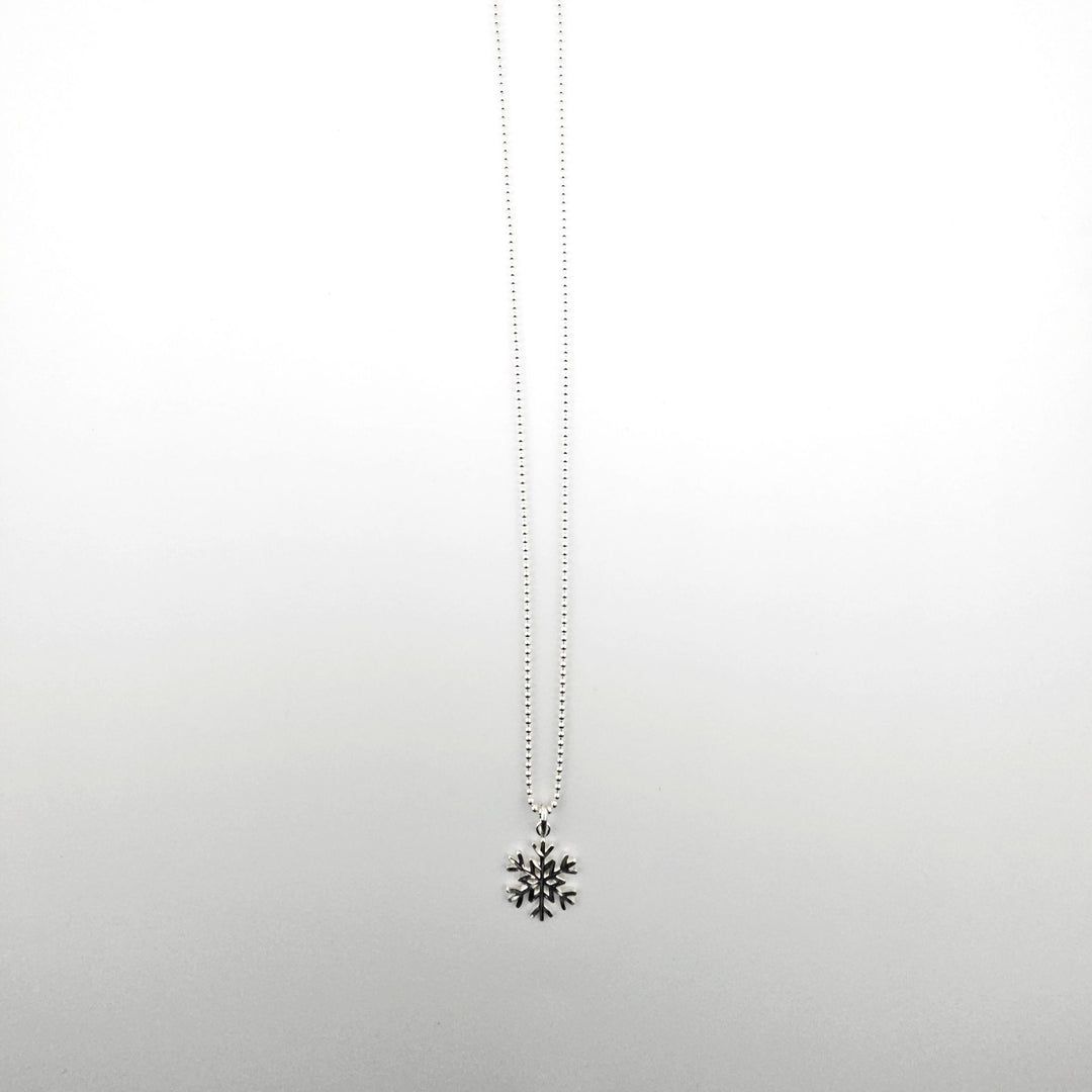 Sterling silver snowflake necklace on a white background.