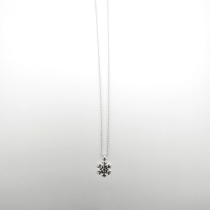 Sterling silver snowflake necklace on a white background.