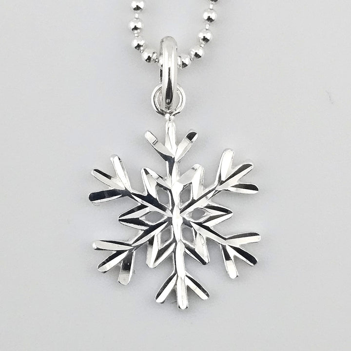 Close-up of sterling silver snowflake pendant with polished finish.