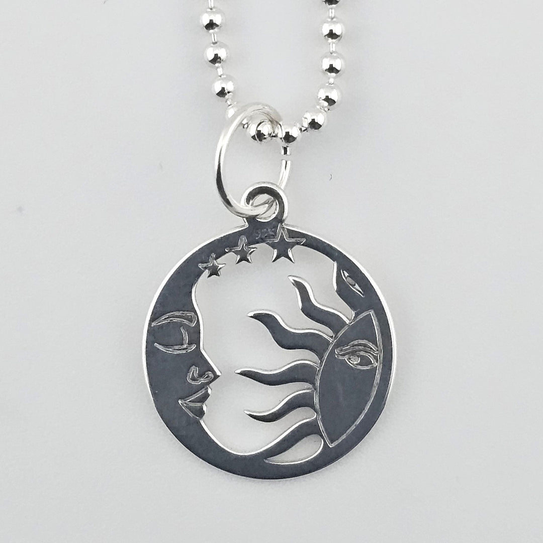 Close-up of sterling silver sun and moon harmony pendant with celestial detailing.