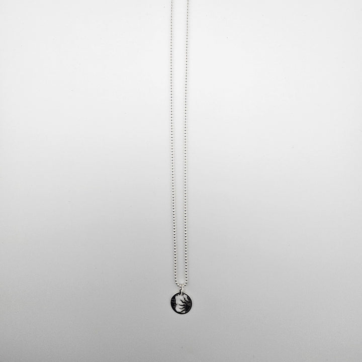 Sterling silver sun and moon harmony necklace displayed on a light background.