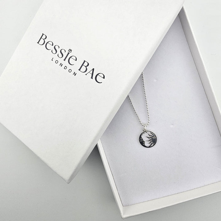 Sterling silver sun and moon harmony necklace shown beside Bessie Bae branded packaging.